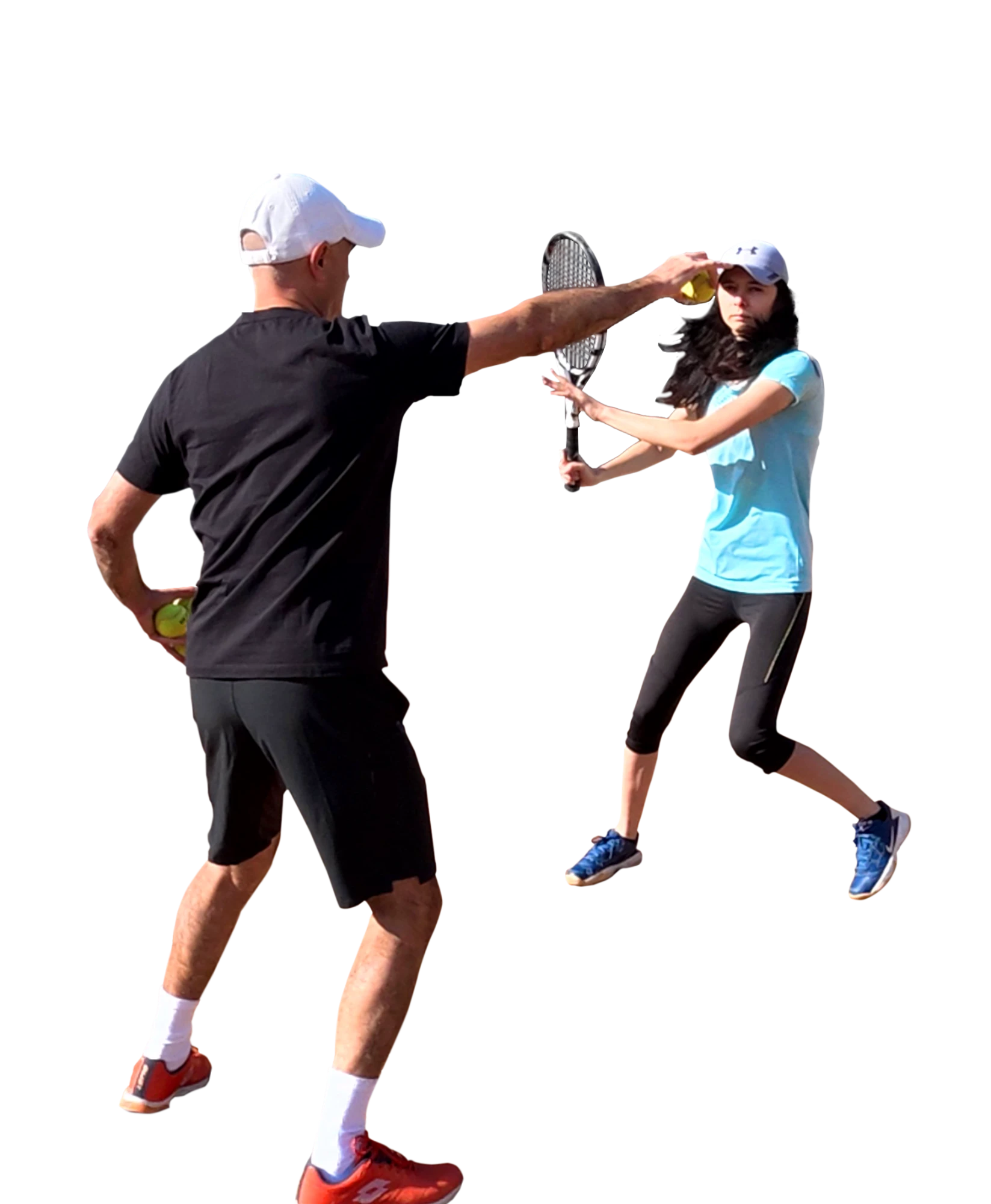 Tennis coach feeding a ball to a player in a ready position during a lesson Tennis coach feeding a ball to a player in a ready position during a lesson